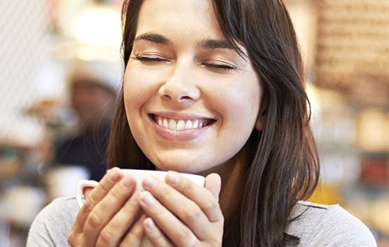 Woman smiling over coffee mug