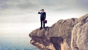 Businessman on cliff looking with binoculars