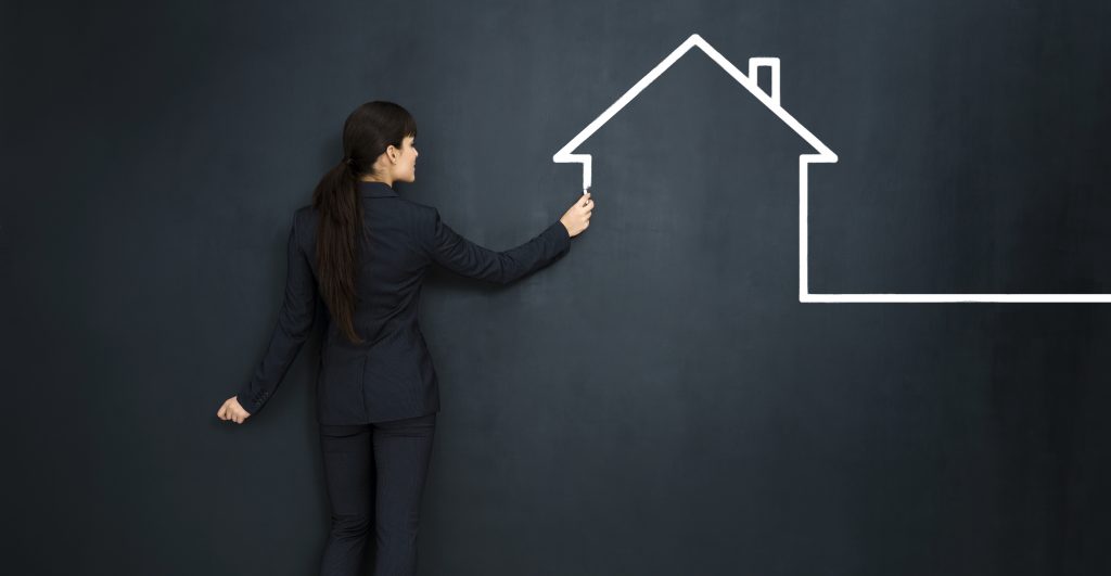 Woman drawing a house on big blackboard