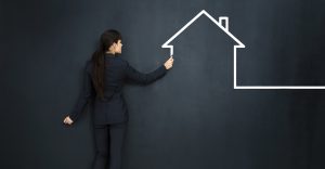 Woman drawing a house on big blackboard Woman drawing a house on big blackboard