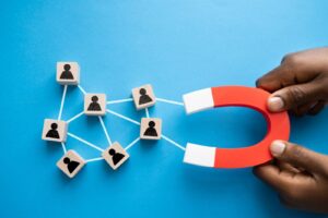 hands holding a magnet pulling user icons symbolizing lead generation in real estate