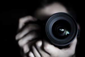 Picture of a camera lense with photographer blurry in background