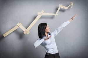 Excited businesswoman in front of pointing up business chart.