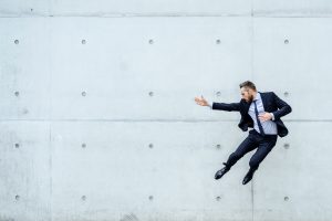 Businessman doing a karate kick Portrait of an bearded young businessman in front of a concrete wall Businessman doing a karate kick