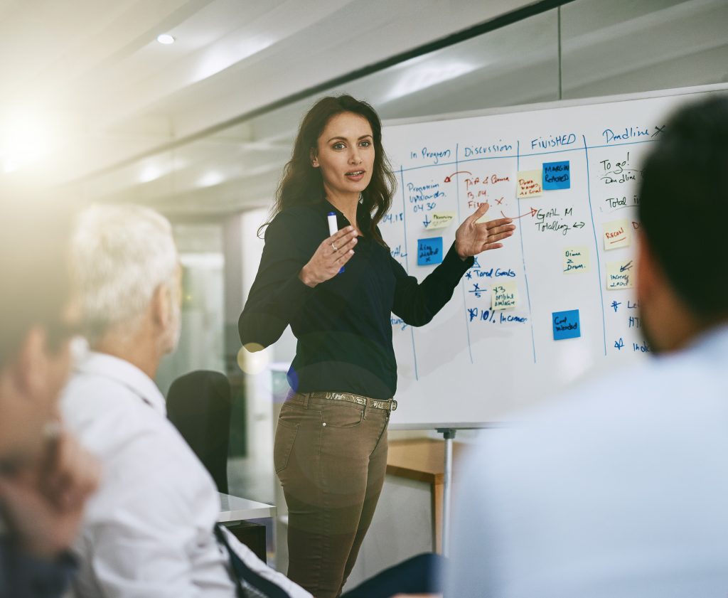 Woman giving presentation in front of white board