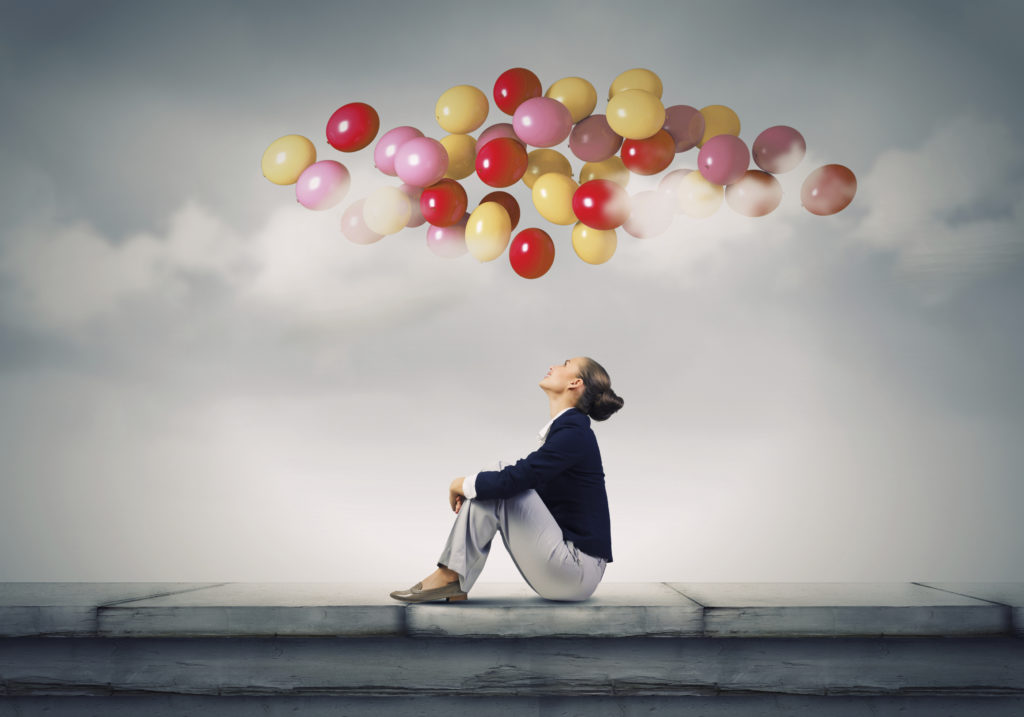 Business woman looking up at colorful balloons