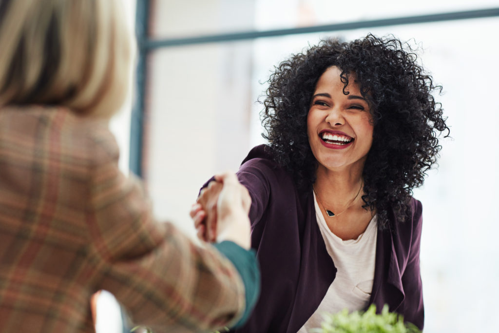 Two women shaking hands, big smile