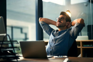 Man sitting back smiling at desk