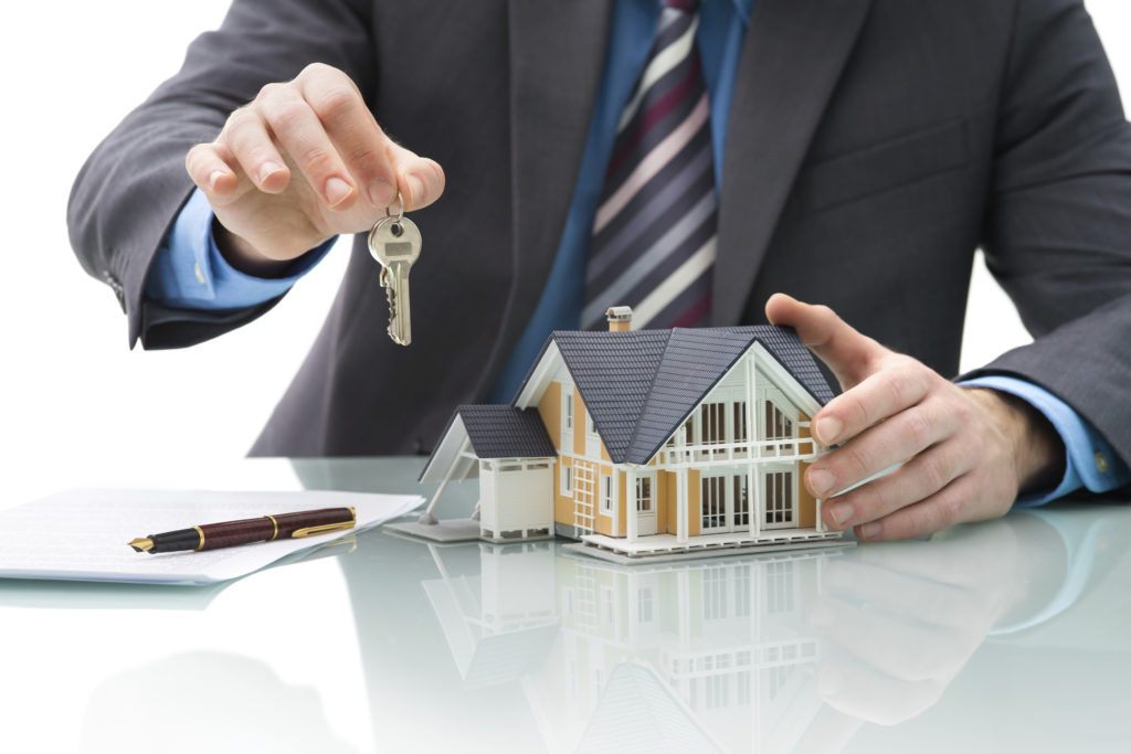Real estate agent holding key next to figurine of house