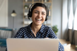 Woman laughing wearing headset in front of computer