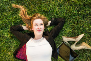 Woman looking up at sky, laying on grass, relaxing