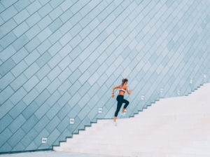 woman running up staircase, blue background wall