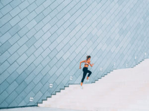 Running Up The Stairs woman running up staircase, blue background wall