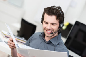 Male customer service with headset looking in notebook