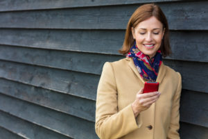 Smiling woman with cell phone by black wall