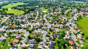 Aerial shot of a spacious suburban neighborhood with houses, green lawns, and curved streets