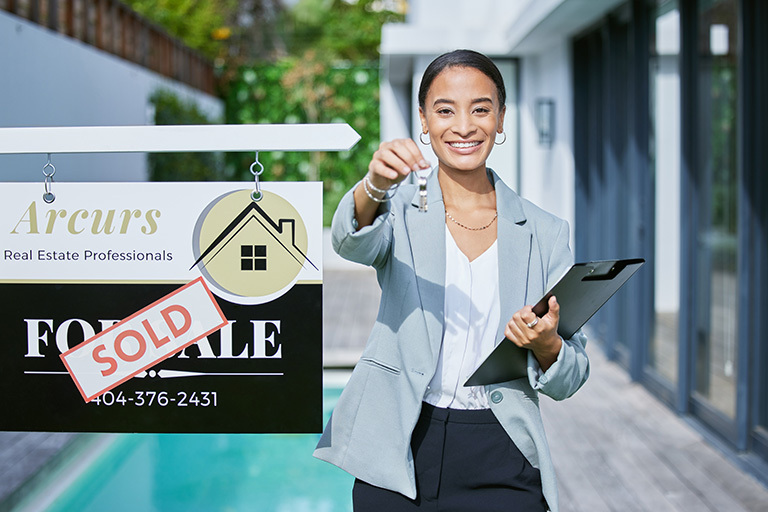A top-performing real estate agent smiles and hands the keys to a buyer after closing another deal