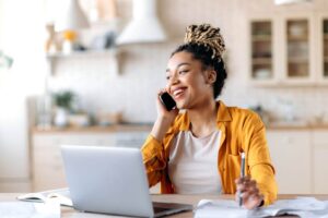 maximize-your-real-estate-lead-generation (1) young successful female real estate agent talking on the phone with a client in front of a laptop
