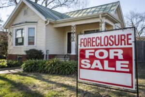 a house with a sign in front saying foreclosure for sale