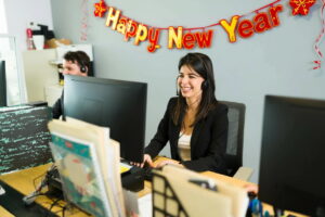 Agent on call in office with Happy New Year banner on wall behind her
