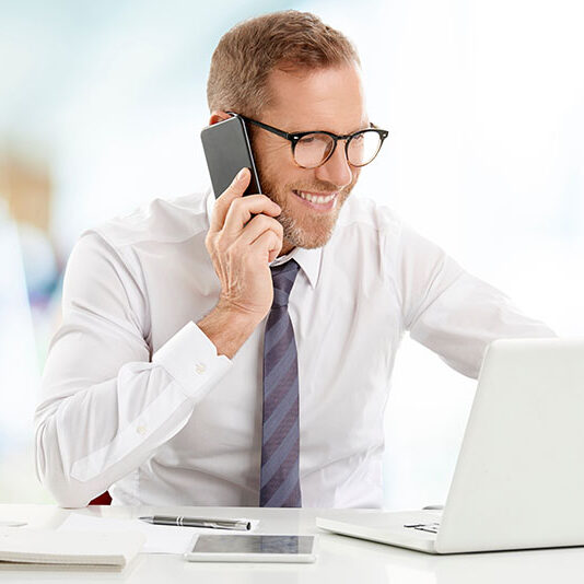 Happy businessman on cellphone at desk
